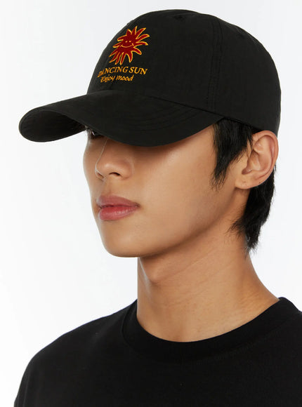 Embroidered Sun Logo Cap IL515 Black side close-up on model showing three-quarter angle of structured brim and embroidered sun logo on panel