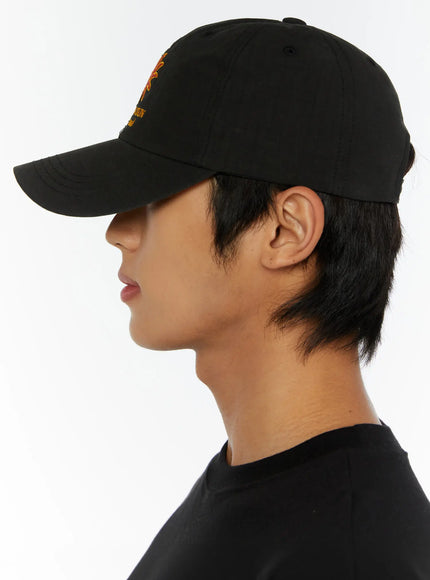 Embroidered Sun Logo Cap IL515 Black side profile close-up on model showing brim silhouette and cap fit from left side with black tee