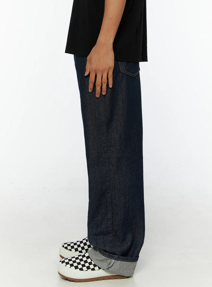 Emil Dark-Wash Straight-Leg Jeans IL515 Dark blue side close-up on model showing back pocket stitching detail wide-leg raw denim and rolled gray cuff hem