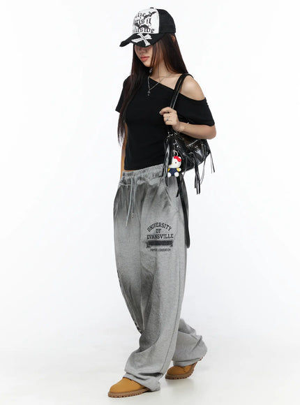 Faux Leather Shoulder Bag CL527 Black full outfit view on model wearing cap, crossbody carry style with Hello Kitty charm, styled with black crop top and grey wide-leg sweatpants and tan boots