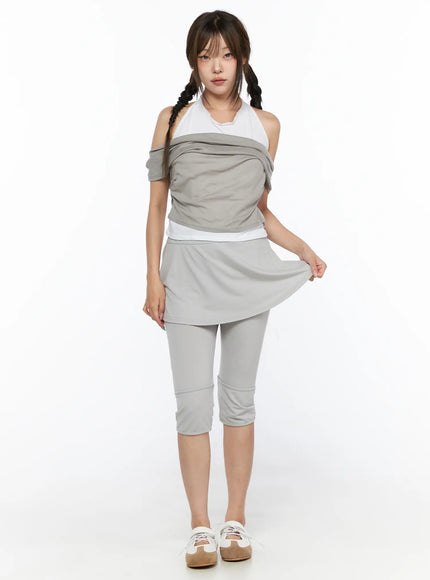 Flare Skort CL517 Light gray full-length front view on model standing, lifting skirt hem to reveal capri leggings beneath, styled with gray draped top and white sneakers