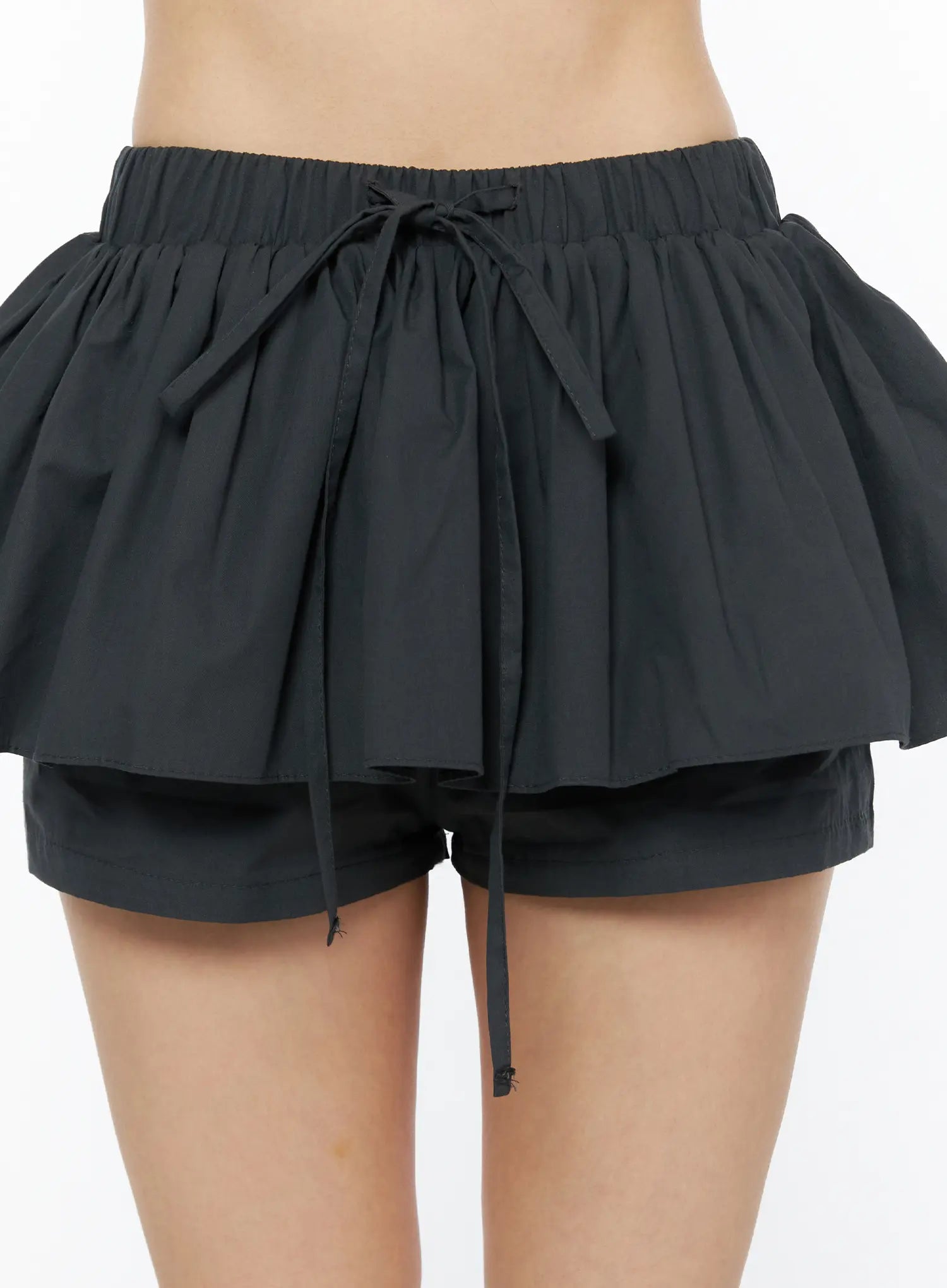 Flared Mini Skort CL501 Black front close-up detail shot on model showing elastic waistband, bow drawstring tie and double ruffle layer over inner shorts