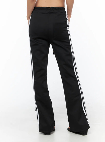 Flared Striped Track Pants CU524 Black back shot on model showing rear pocket, back seam, and triple white side stripes on flared hem