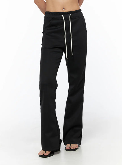 Flared Striped Track Pants CU524 Black front shot on model showing full-length flared silhouette with cream drawstring waist, no side stripes visible