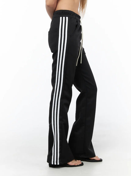 Flared Striped Track Pants CU524 Black side shot on model showing full-length triple white stripe detail along flared leg silhouette