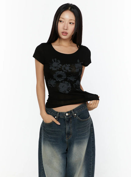 Floral Graphic Round-Shoulder Top CU529 Black front shot on model with scoop neck, subtle tone-on-tone floral graphic print, slim cropped fit paired with wide-leg jeans