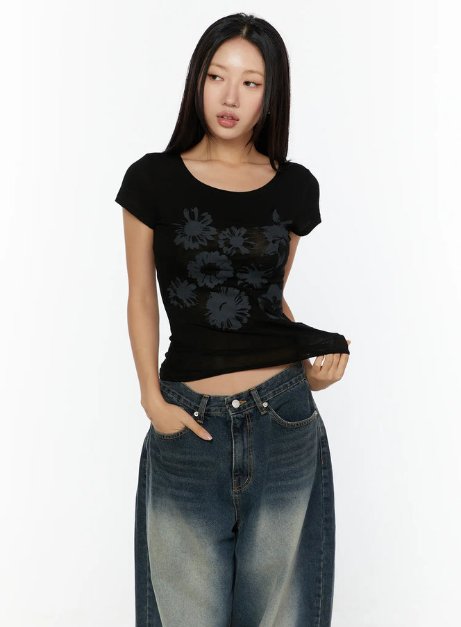 Floral Graphic Round-Shoulder Top CU529 Black front shot on model with scoop neck, subtle tone-on-tone floral graphic print, slim cropped fit paired with wide-leg jeans