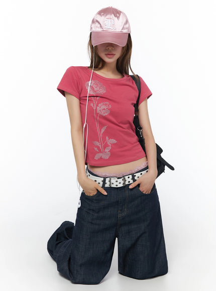 Floral Graphic Short Sleeve Top IU525 Dark pink front kneeling shot styled with pink cap earphones crossbody bag star-studded belt lace waistband wide-leg denim