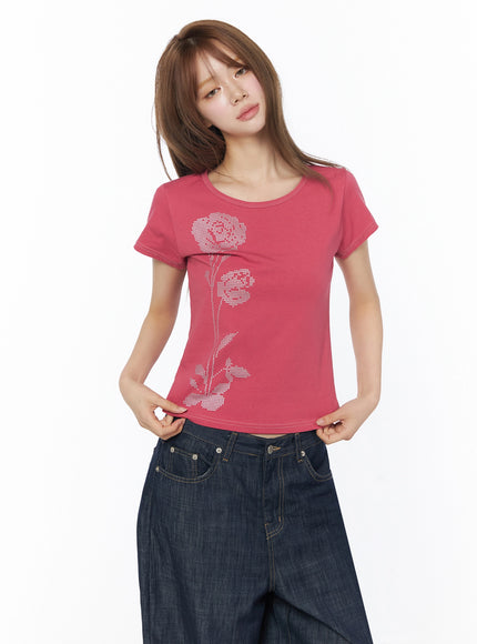 Floral Graphic Short Sleeve Top IU525 Dark pink front shot model looking at camera hands at waist holding hem showing full rose graphic and cropped fit