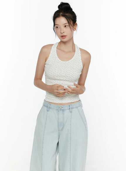 Floral Halter Top CL521 White front view on model with hands clasped at waist, showing fitted ribbed floral crop top tucked above light wash wide-leg jeans
