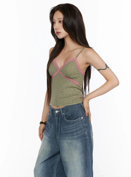 Floral Lace Trim Cami CU530 Green side shot model standing with hand on hip wearing green floral ribbed cami with pink lace cross trim paired with blue wide-leg denim