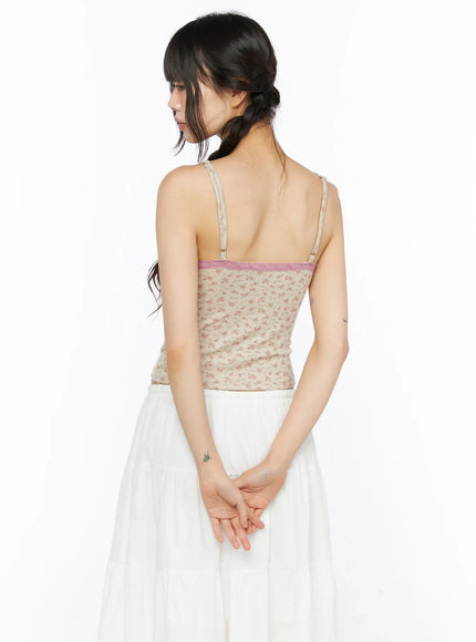 Floral Lace Trim Cami CU530 Beige back shot model standing with hands clasped showing beige floral ribbed back pink lace upper band and adjustable straps over white skirt