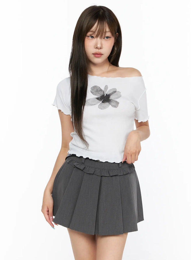 Floral Print Tee CL517 White front shot model wearing off-shoulder fitted ribbed tee with dark floral graphic print and lettuce-edge neckline, paired with gray pleated mini skirt