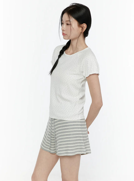 Floral Puff Short Sleeve Top IL506 White side view on model with braided hair looking left hands in pocket styled with gray striped shorts