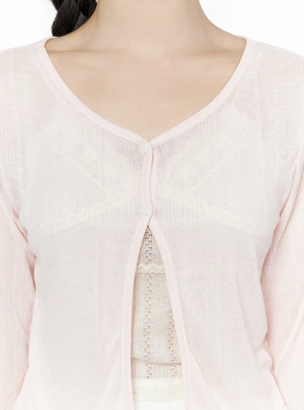 Flower Button Ribbed Cardigan IU525 Light pink close-up detail of V-neckline single button closure and sheer ribbed knit texture layered over cream lace camisole
