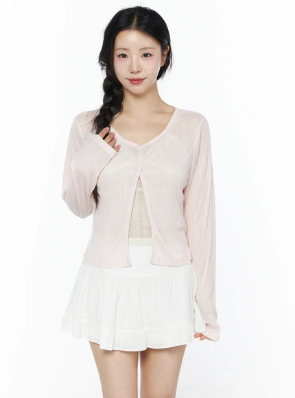 Flower Button Ribbed Cardigan IU525 Light pink front model half-body shot hand touching hair showing V-neck open front and sheer lightweight ribbed knit fabric with lace camisole underneath
