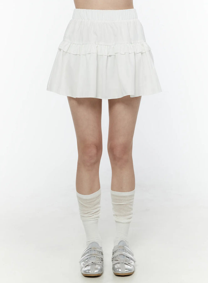 LEWKIN Frill Tiered Mini Skirt IL506 White front shot on model wearing white knee socks and silver flats, elastic waistband and double ruffle tiers visible