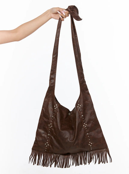 LEWKIN Fringe Studded Shoulder Bag CU524 Brown front hanger shot held by model hand showing full bag silhouette with fringe hem and silver studs
