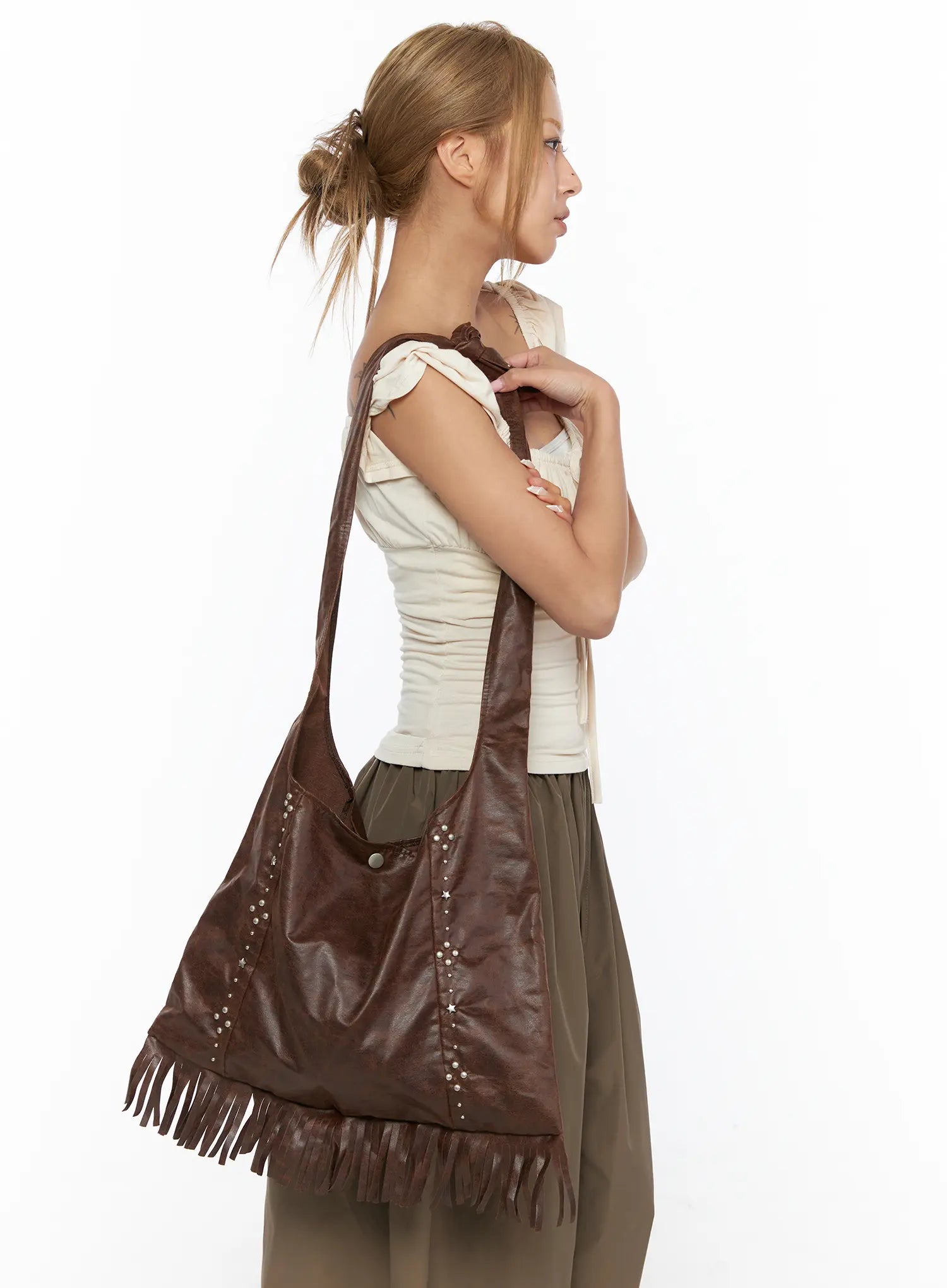 Fringe Studded Shoulder Bag CU524 Brown side view on model shoulder worn over cream ruched top showing studded leather texture and fringe trim