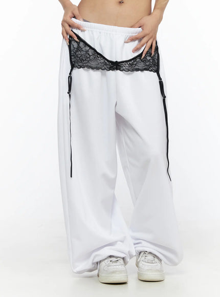 Garter Belt Graphic Wide-Leg Sweatpants CL528 White front view on model hands on waistband, showing black lace garter band with ribbon garter straps and wide-leg hem
