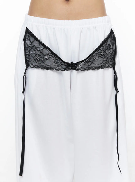 Garter Belt Graphic Wide-Leg Sweatpants CL528 White close-up detail of black floral lace garter band with ribbon straps and bow center front