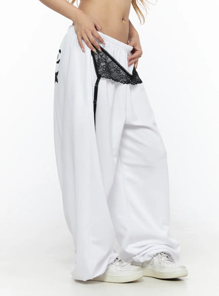 Garter Belt Graphic Wide-Leg Sweatpants CL528 White side view on model pulling waistband, showing black lace garter and garter clip strap detail