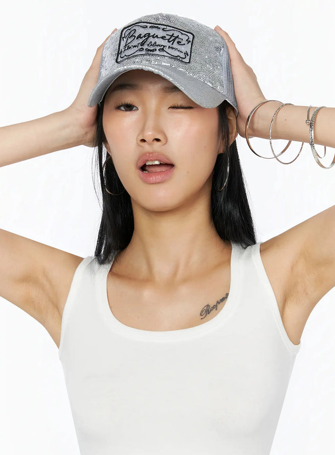 LEWKIN Glitter Patch Trucker Cap IL509 Silver close-up front on model hands raised holding brim sequin texture and Baguette embroidered patch detail