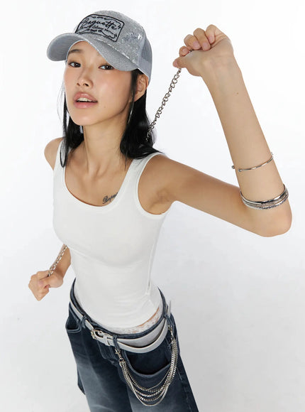 Glitter Patch Trucker Cap IL509 Silver three-quarter front on model holding silver chain arms raised styled with white tank and dark denim
