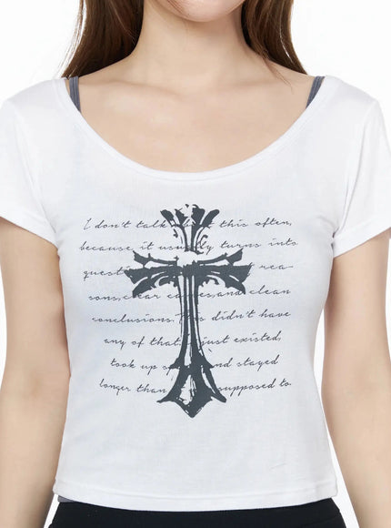 Gothic Cross Slim Fit Top IU525 White close-up front detail shot on model, dark gothic cross overlaid with cursive script print, scoop neckline, inner strap visible