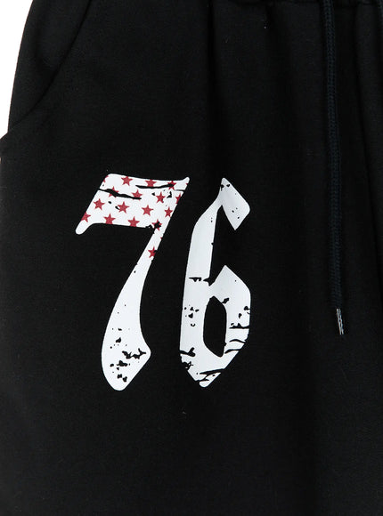 Graphic Bermuda Shorts CL524 Black close-up detail of distressed white and red 76 star-flag graphic print on black cotton fabric with drawstring