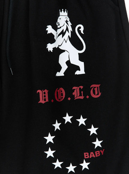 Graphic Bermuda Shorts CL524 Black close-up detail of white crowned lion, red V.O.L.T old-English text and white BABY star circle print on black fabric