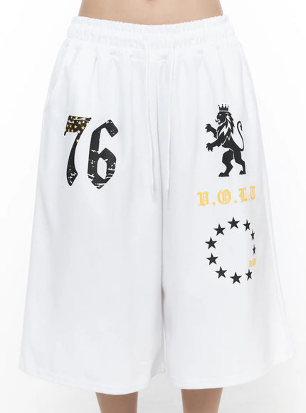 Graphic Bermuda Shorts CL524 White close-up front on model showing large 76, crowned lion, yellow V.O.L.T text and BABY star circle graphic prints
