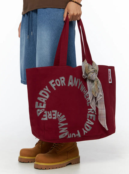 LEWKIN Graphic Canvas Tote Bag IL520 Dark red front model shot held by hand with plaid scarf accent styled with denim shorts and boots