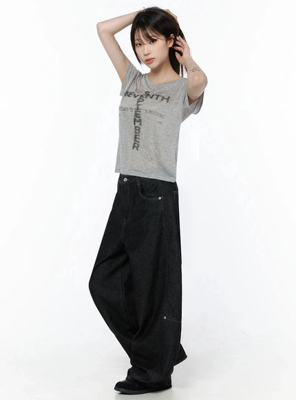 Graphic Casual Tee IL502 Gray side shot model arms raised hand behind head semi-sheer crop tee with cross graphic styled with oversized black wide-leg jeans