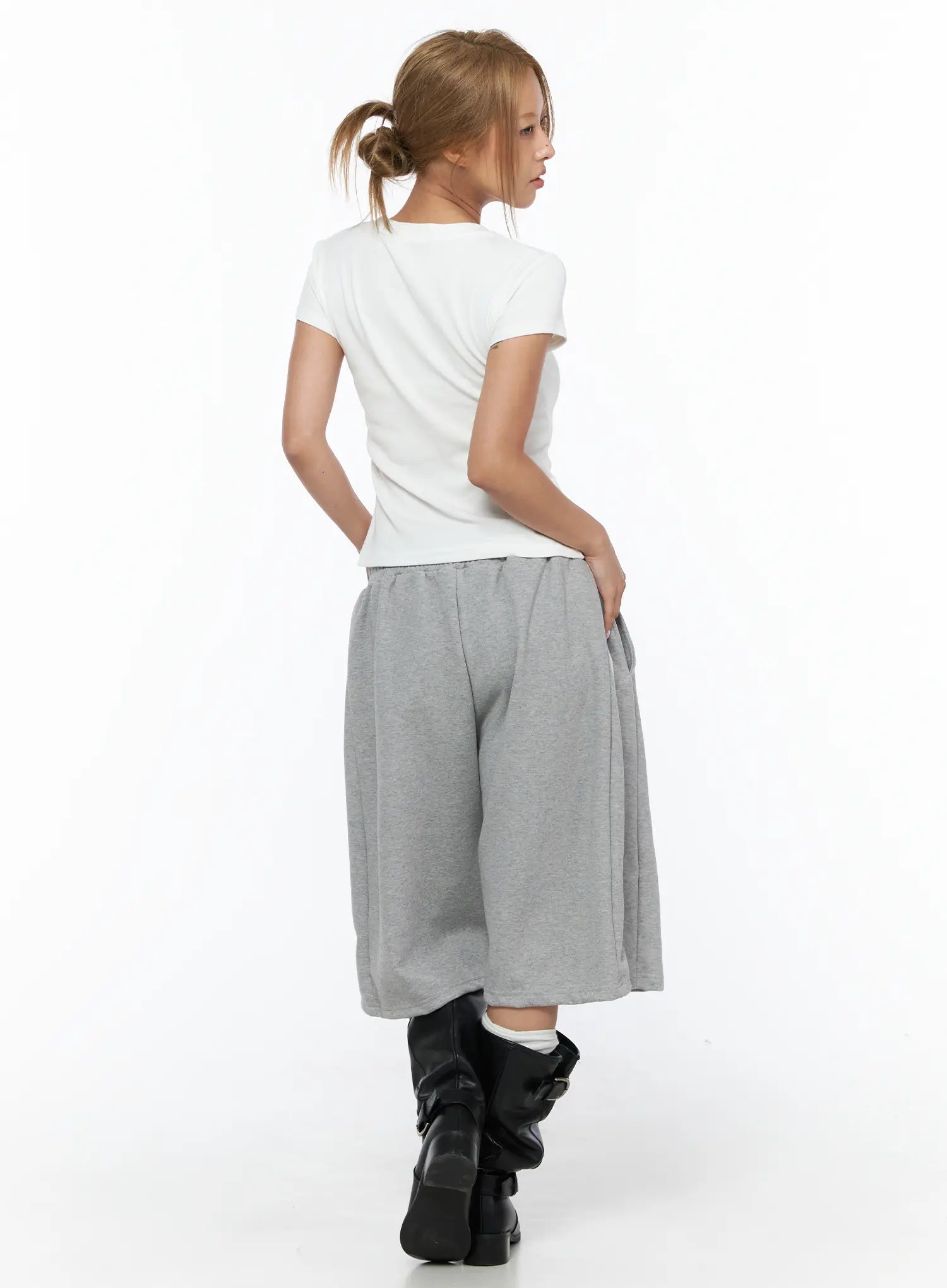 Graphic Crop Tee CU523 White back shot on model with ponytail, plain white back panel showing slim crop cut and short sleeves, styled with gray wide-leg sweatpants and black boots