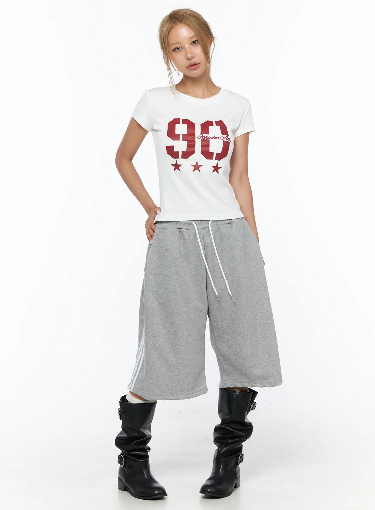 Graphic Crop Tee CU523 White front full-body shot on model standing straight, red 90 Fousche Arts graphic, cropped hem, styled with gray wide-leg pants and black boots