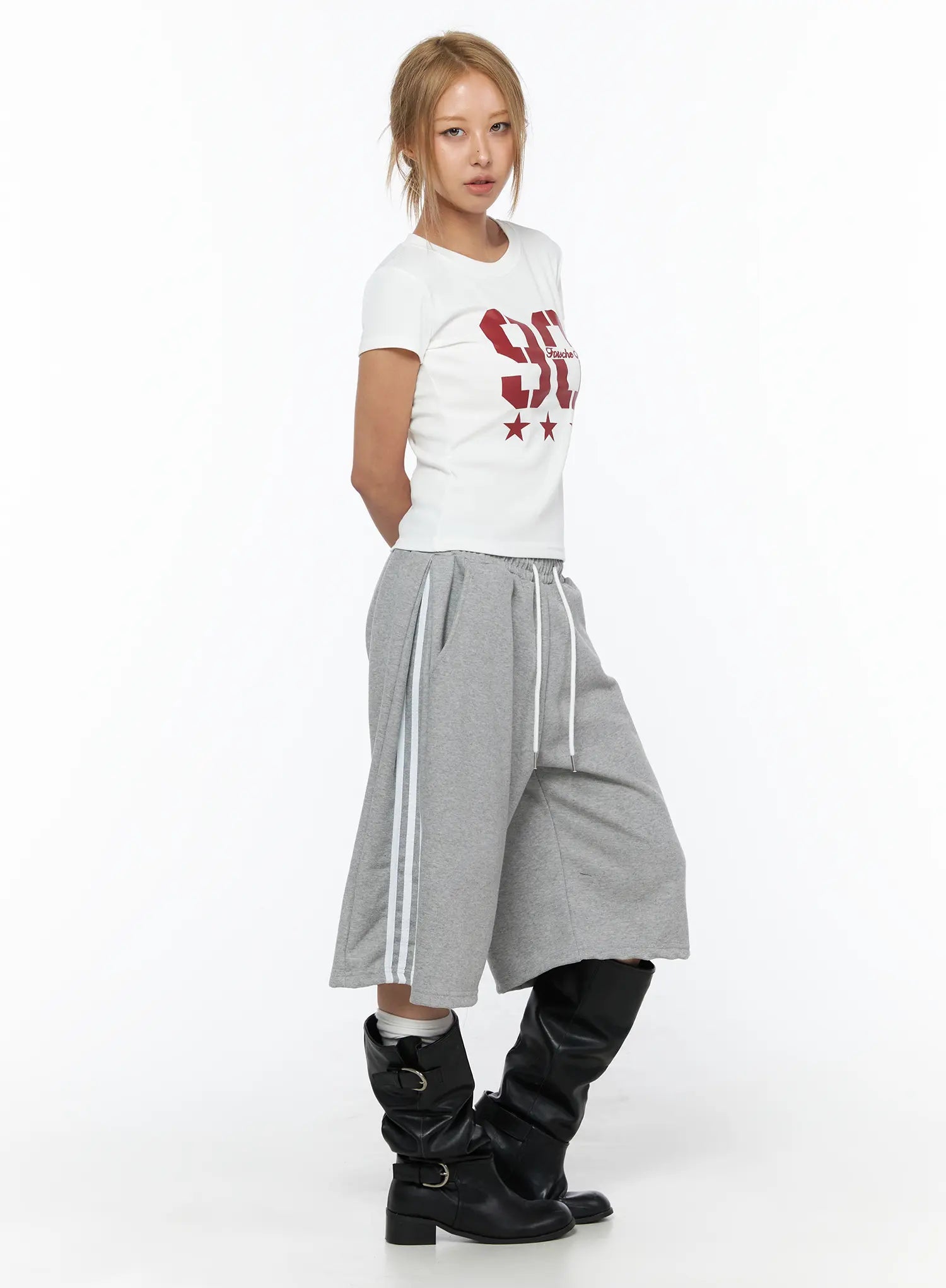 Graphic Crop Tee CU523 White side shot on model turning left, red 90 graphic partially visible, slim crop fit, styled with gray striped wide-leg pants and black boots