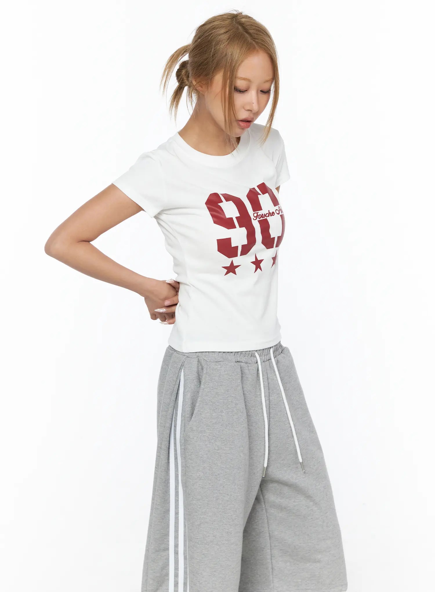 Graphic Crop Tee CU523 White S/M side-angle shot on model with ponytail, red 90 star graphic print, slim cotton crop fit, styled with gray wide-leg sweatpants