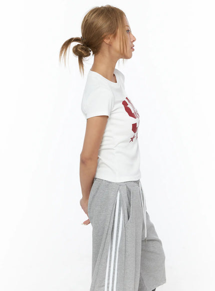 Graphic Crop Tee CU523 White side profile shot on model, red 90 star graphic on chest, slim cropped cotton tee, styled with gray wide-leg drawstring pants
