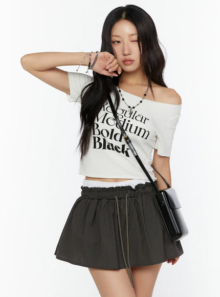 LEWKIN Graphic Cropped Tee CU526 White M/L front model shot off-shoulder styled with black graphic print, accessorized with crossbody bag and layered necklaces