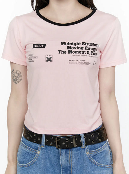 Graphic Cropped Tee IL521 Light pink close-up front detail on model showing XR-91 badge, Midnight Structure archive graphic print, and black contrast neckline trim