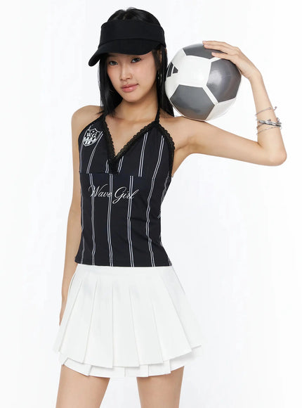 LEWKIN Graphic Lace Halter Top IL509 Black front model shot wearing cap holding soccer ball styled with white pleated mini skirt S/M