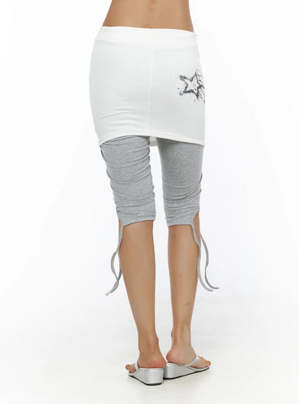 Graphic Layered Skort CL503 Gray back shot on model showing plain white skirt overlay with star print detail and gray ruched leggings with ankle ties