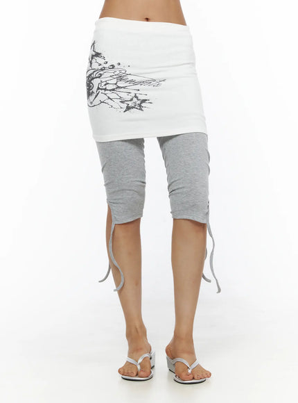 Graphic Layered Skort CL503 Gray front shot on model showing white skirt layer with full wing graphic and gray ruched leggings with ankle ties and sandals