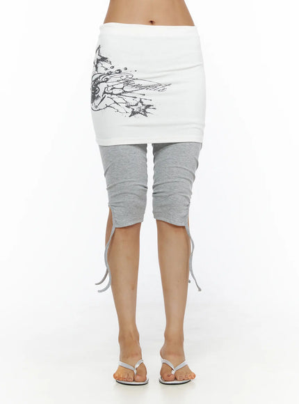 Graphic Layered Skort CL503 Gray front shot on model showing white mini skirt with dark wing graphic over gray capri leggings with tie hem