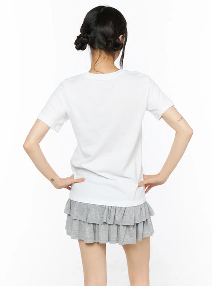 Graphic Meow Tee CU530 White back view on model, plain white cotton short-sleeve tee showing clean back silhouette, styled with grey ruffle mini skirt
