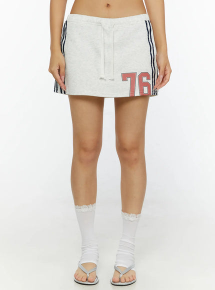 Graphic Mini Skirt CL515 Light Gray front close-up shot on model showing drawstring waistband, red 76 number print, navy side stripes, heathered fleece fabric