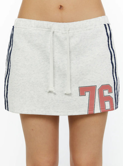 Graphic Mini Skirt CL515 Light Gray close-up front shot on model showing drawstring waistband, navy side stripes, and red 76 number graphic on hem