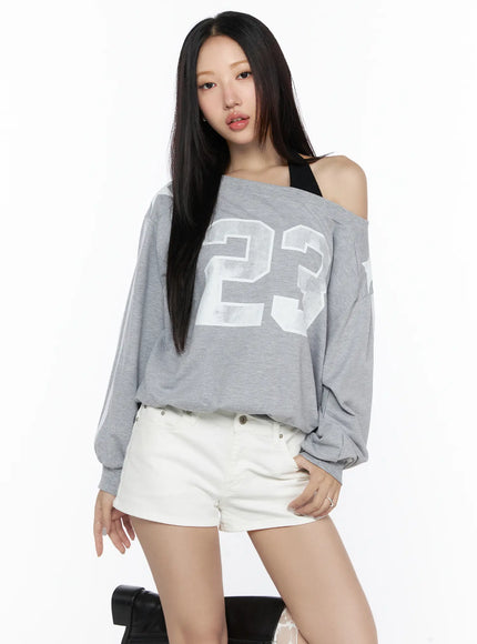 Graphic Off-Shoulder Sweatshirt CL527 Gray front shot on model with 23 graphic print asymmetric neckline black bra strap visible white shorts