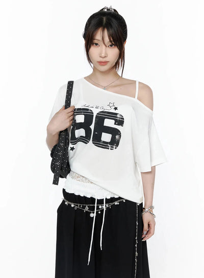 LEWKIN Graphic Off-Shoulder T-Shirt IL506 White front view on model with updo hair, one-shoulder strap, black 86 distressed print, lace hem drawstring, styled with chain belt and bag